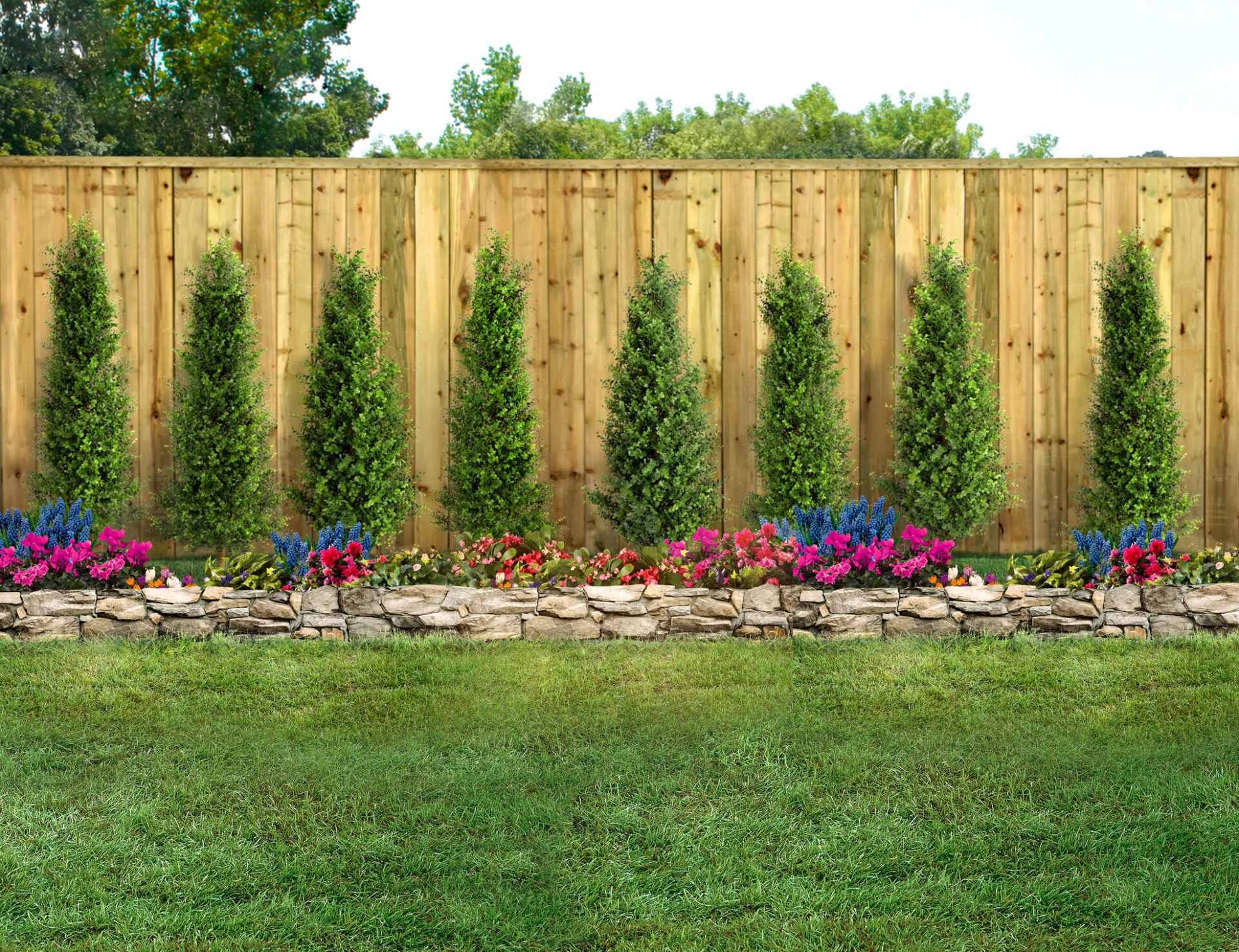 A well-maintained garden with a wooden fence, neatly arranged colorful flowers, and evenly spaced evergreen trees. Green grass covers the foreground.